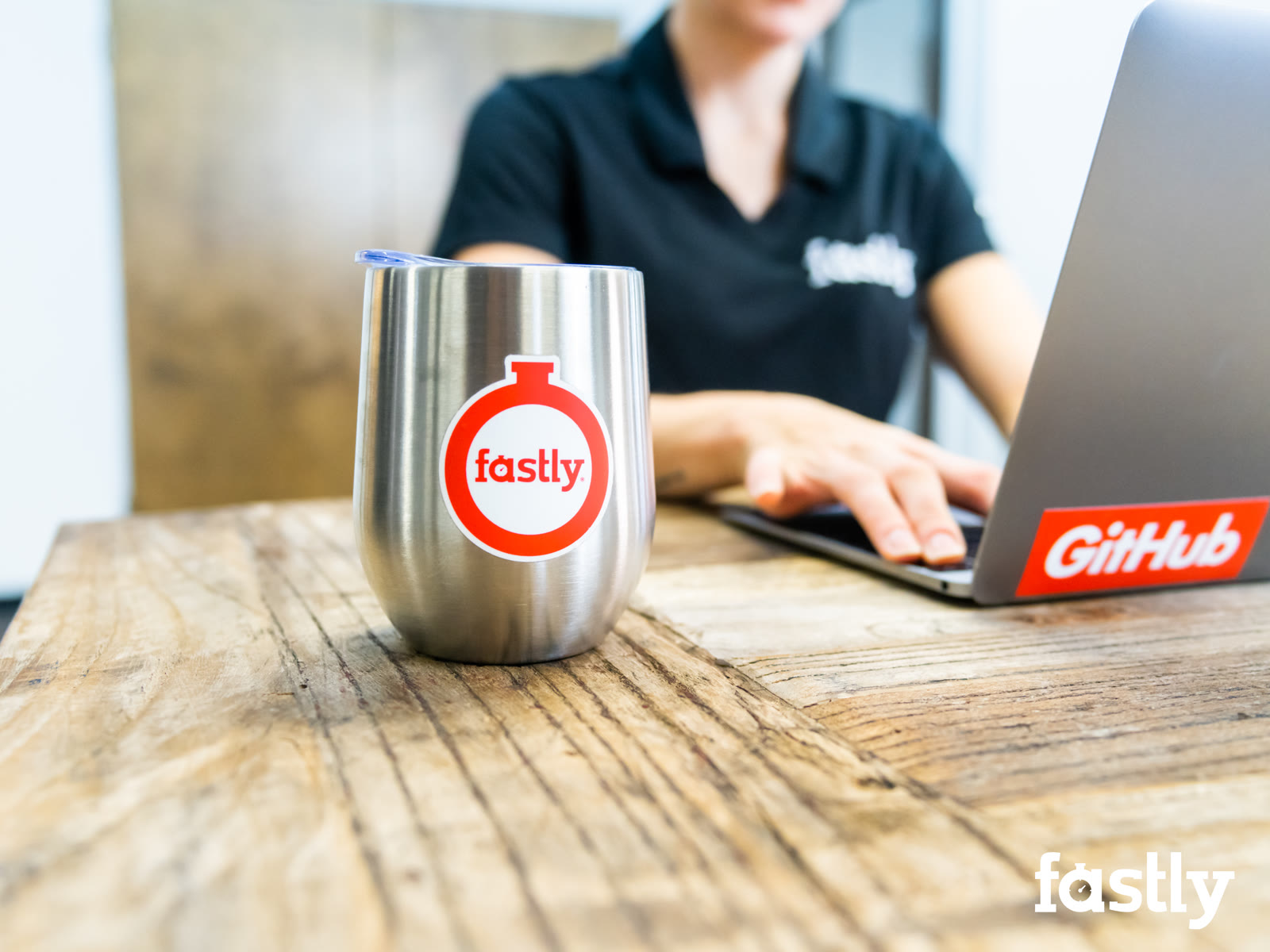 Fastly-branded mug beside a laptop with a GitHub sticker