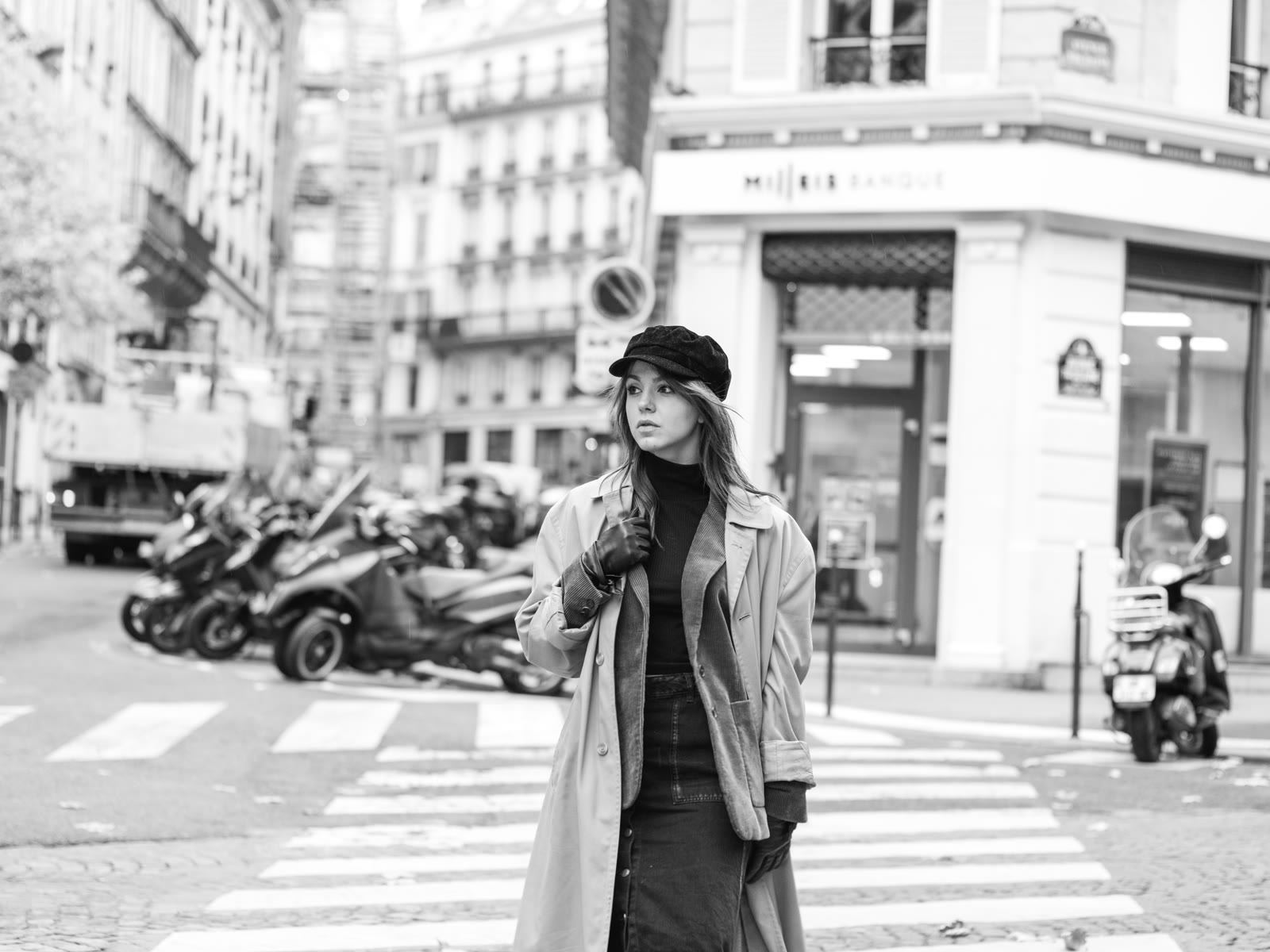 Black-and-white frame of a woman crossing a Paris intersection