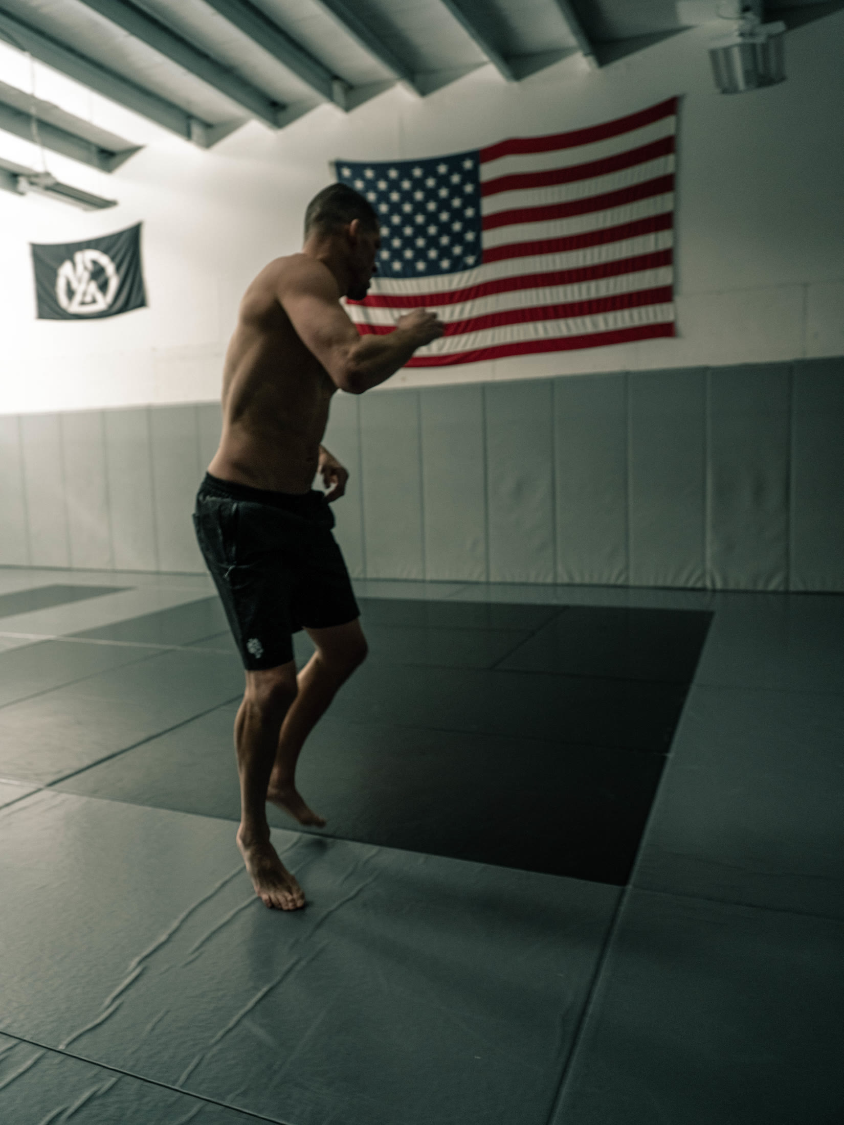 Nate Diaz moving across the mats beneath an American flag