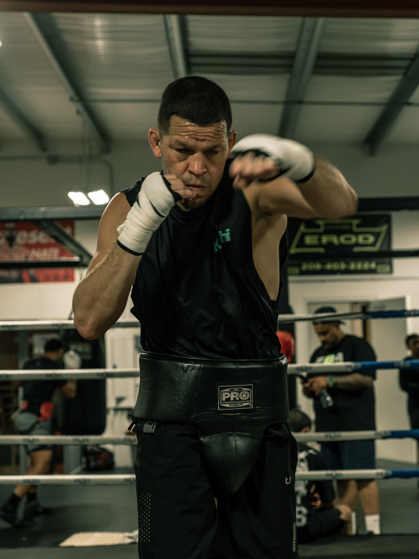 Nate Diaz throwing a strike in dark gym light