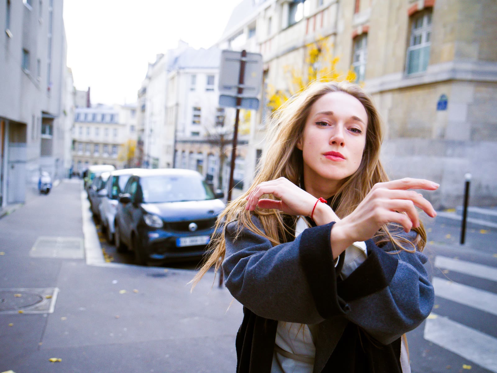 A woman dancing with raised arms in a Paris crosswalk
