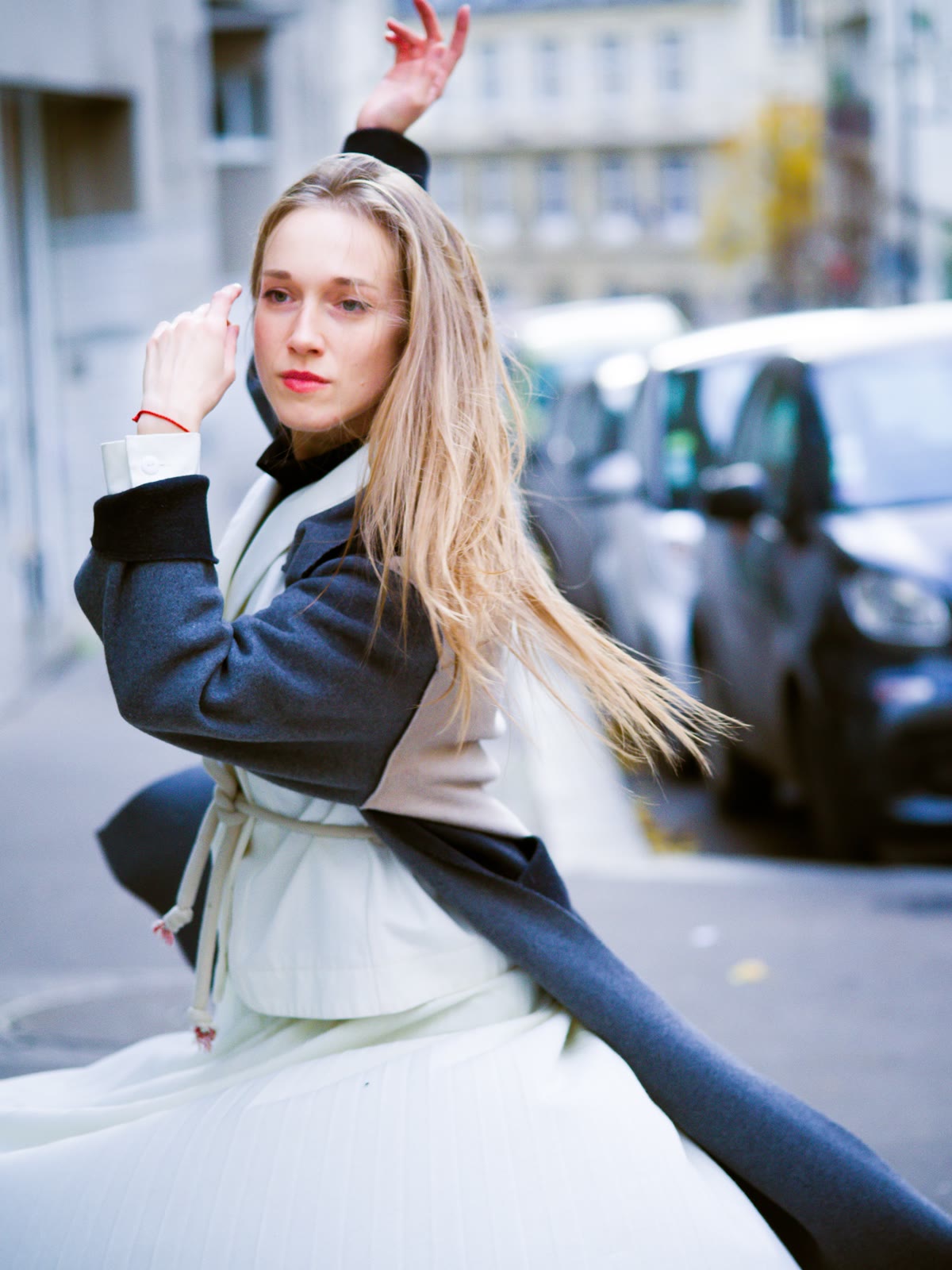 A woman mid-spin in a white coat
